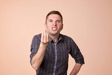 Caucasian middle aged man looking angry showing italian gesture over brown background