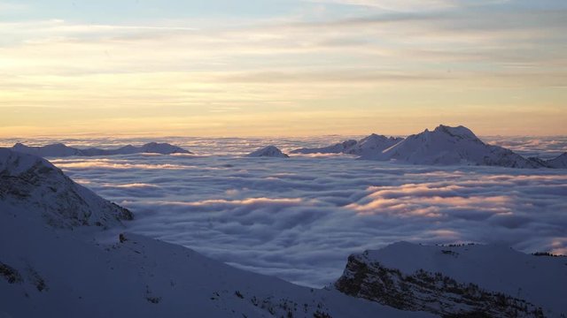 Timelapse of mountains with a clouds sea, at sunset in winter.