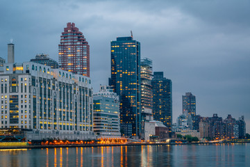 Naklejka premium Manhattan and the East River at night, seen from Roosevelt Island, in New York City.