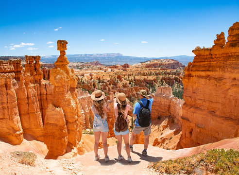 Family standing next to Thor's Hammer hoodoo on top of  mountain looking at beautiful view. Bryce Canyon National Park, Utah, USA