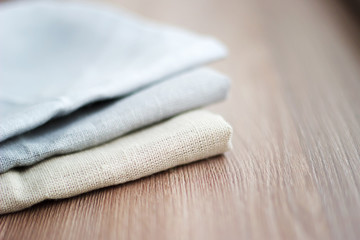 Three kinds of different cloth in a pile on a brown wooden table close up.