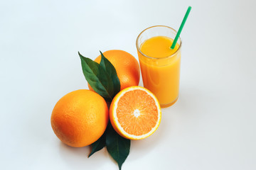 Glass with orange juice next to orange slices on a white background.