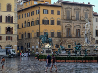 Neptune looking down on tourists in the rain in Florence