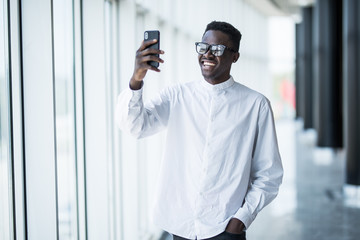 Portrait of an African American man in smarphone on the background of office buildings.