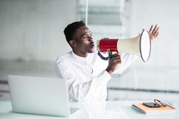 Afro businessman scream yelling through a megaphone in the office