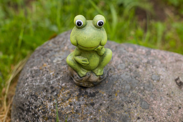 Decorative frog in the garden.ceramic green frog figurine, frog sitting on the stones.Copy space
