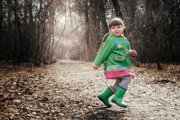 the girl is poking on puddles in rubber boots