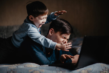 child playing with dad near laptop