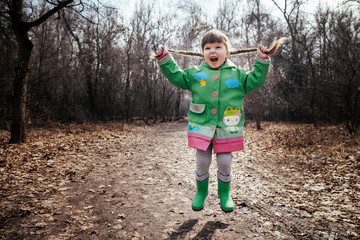 the girl is poking on puddles in rubber boots