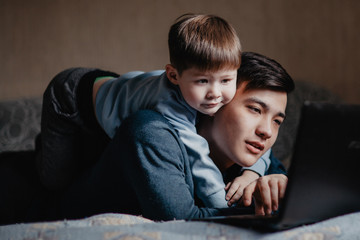 child playing with dad near laptop