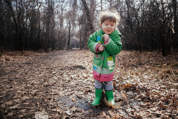 the girl is poking on puddles in rubber boots
