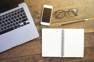Top view of working desk with computer mobile phone and blank note book on wooden table