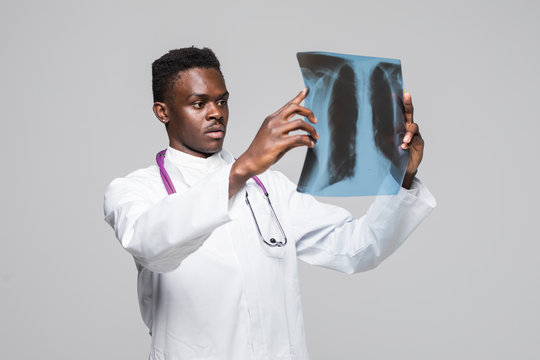 Afro american young medic doctor looking at x-ray isolated on gray background
