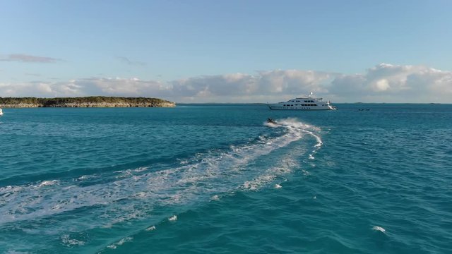 Drone following male and female couple towards islands, yachts, and boats in the Bahamas. Aerial footage by DJI Mavic Air.