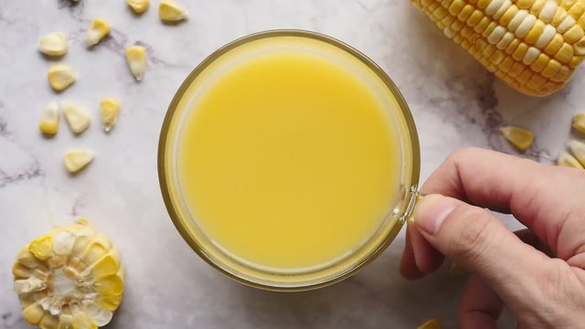 A cup of corn milk and fresh sweet corn on marble table. 