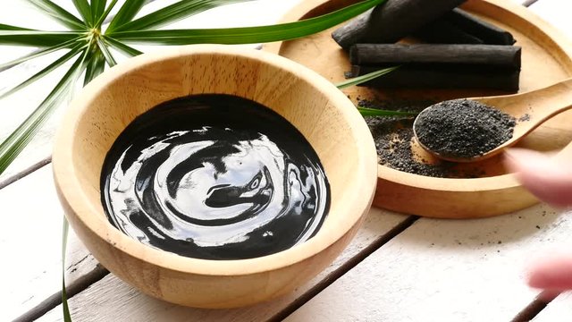Facial mask and scrub by activated charcoal powder and yogurt on wooden table
