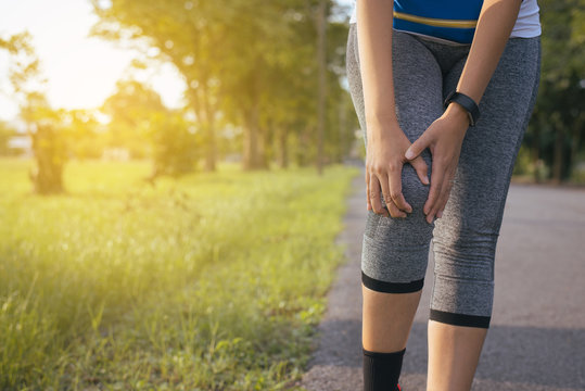 Woman suffering from pain in legs and knee injury after running jogging with workout in park