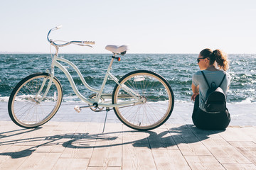 Stylish young woman sitting at the background of blue sea