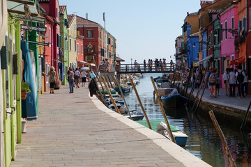 Fototapeta na wymiar Tourists strolling alongside the canal and colorful buildings of Burano