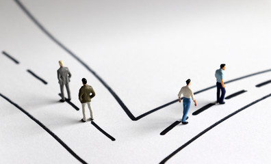 Miniature people standing on two different streets.