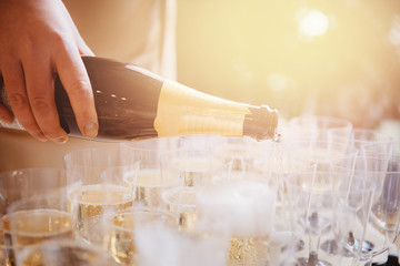 Woman waiter spills champagne from bottle into glasses. caterer banquet