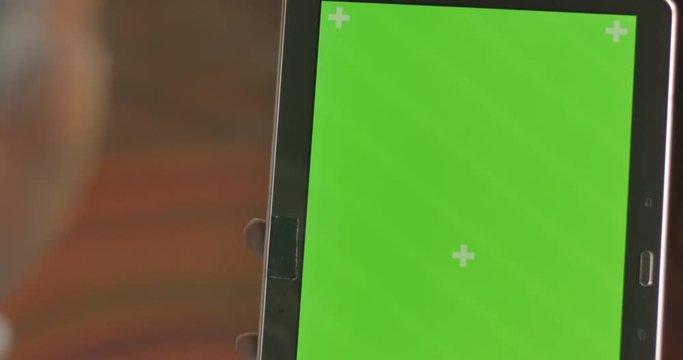 Black hand tapping, and scrolling on a digital tablet green screen display