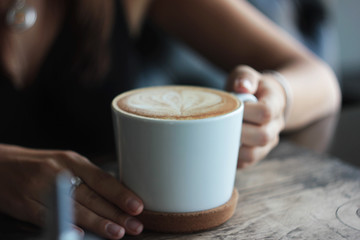 Large white Cup with cappuccino in female hands, selective focus