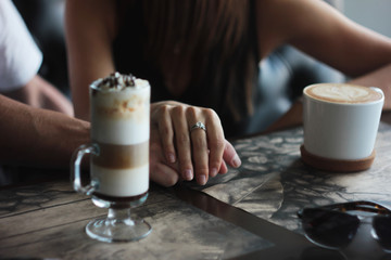 Young couple on date in cafe with cappuccino latte, hand in hand