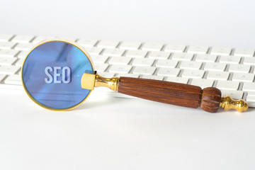 Ein Computer, eine Lupe und SEO Search Engine Optimization