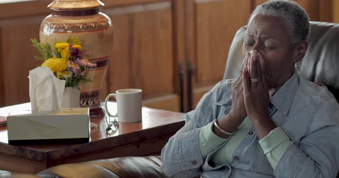 Sick elderly black woman with a cold blowing her nose with a tissue