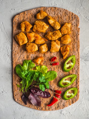 Pieces of fried chicken curry fillet on rye flatbread with vegetables.