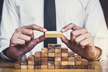 Risk To Make Business Growth Concept With Wooden Blocks, hand of man has piling up and stacking a...