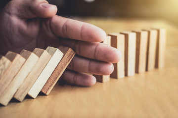 Strategy and successful intervention concept for business, businessman hand Stopping Falling wooden...