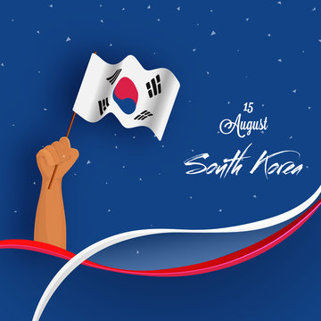 Human hand holding national flag of South Korea on shiny blue background for Korean independence day celebration.