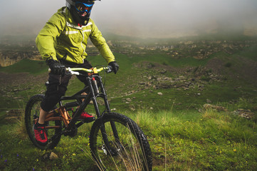 Naklejka premium A man in a mountain helmet riding a mountain bike rides around the beautiful nature in cloudy weather. downhill