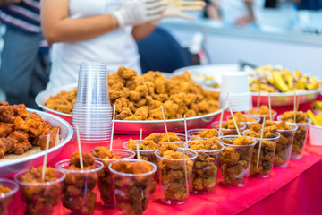 fried chicken is divided into smaller pieces in plastic cups. The chicken is then generally covered in a batter, often consisting of ingredients such as eggs or milk, and a thickener such as flour.
