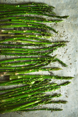 Fresh green Asparagus spears with salt, pepper and oil ready to be grilled or roasted on the baking paper. Asparagus for baking, top view. Cooking food