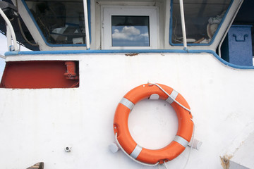 Red coast guard ring buoy hanging on the side of the boat
