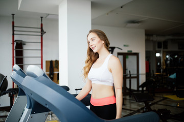 Side view of sporty woman exercising on treadmill in gym