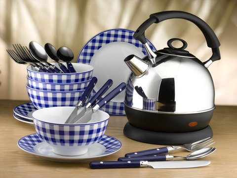 Electric kettle and blue checkered bowls, plates, cutlery on a wooden table. White background