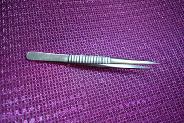 Steel pincer for working on a pink reflective background