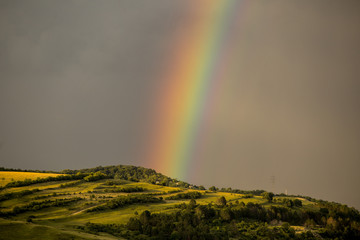 Beautiful rainbow over hills over the town and green hills