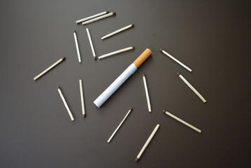 Cigarette with matches on a brown matte background
