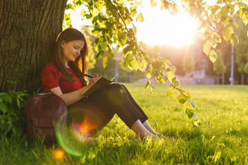 Girl sitting in the summer park and planning her goals and ways with notes. Life coach goals concept