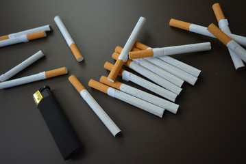 Cigarettes scattered on a brown matte background with a black matte lighter