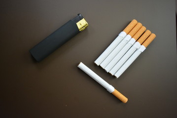 Beautifully laid cigarettes with a black lighter on a brown black background