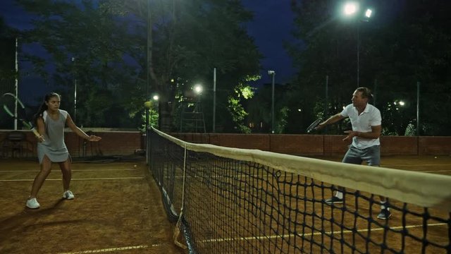 Coacher showing to the girl how to serve the ball