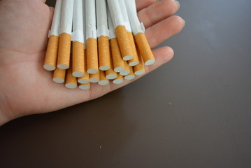 Cigarettes in a female palm on a brown matte background