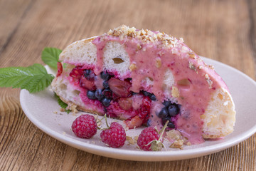 Ciabatta sandwich with raw raspberries, blueberries and cherries on a plate, watered with berry yoghurt with walnuts