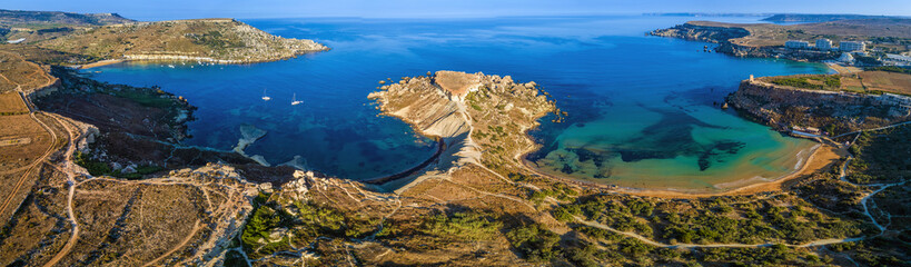 Fototapeta premium Ghajn Tuffieha, Malta - Aerial panoramic view of the coast of Ghajn Tuffieha with Gnejna Bay, Riviera Bay and Golden Bay at sunrise